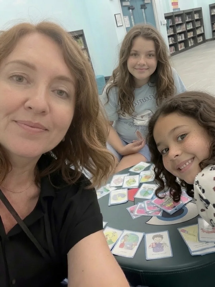 Kat playing a language card game with two young clients, supporting deaf and hard-of-hearing communication skills